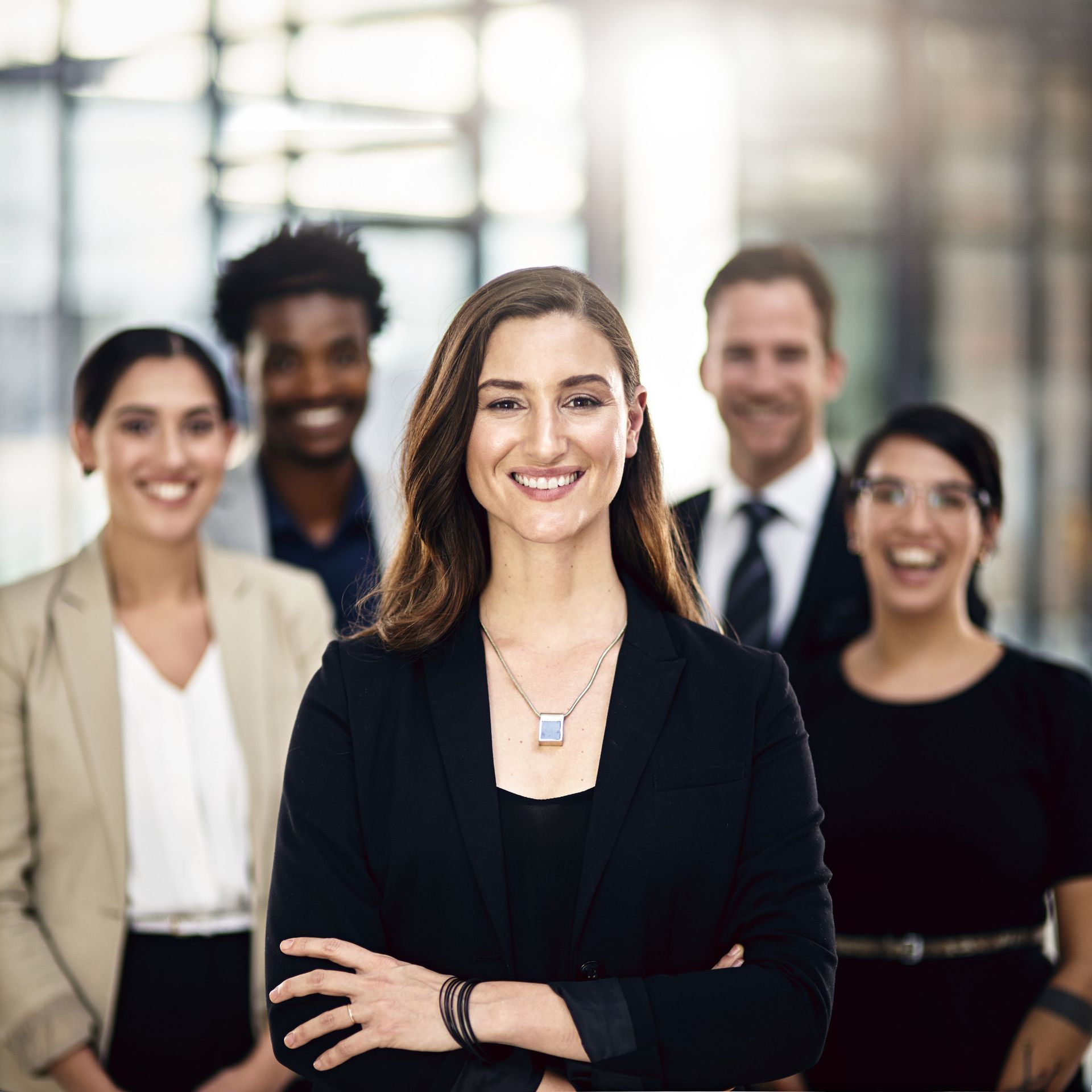 Group of smiling professionals in business attire, posing together indoors.
