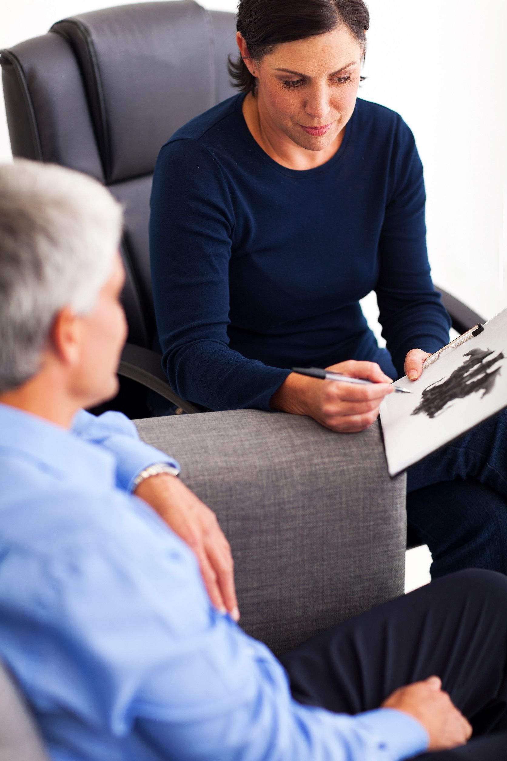 Psychologist showing Rorschach inkblot test to a patient in an office setting.