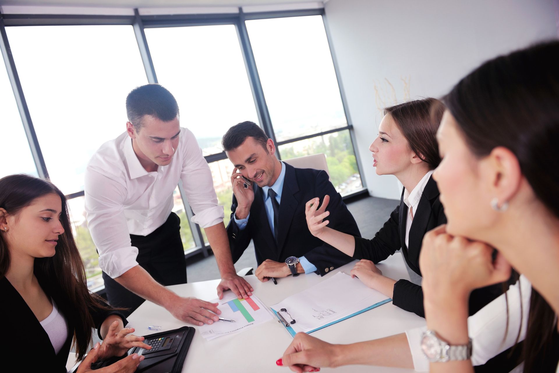 Business team in a meeting, reviewing charts and documents at a round table.