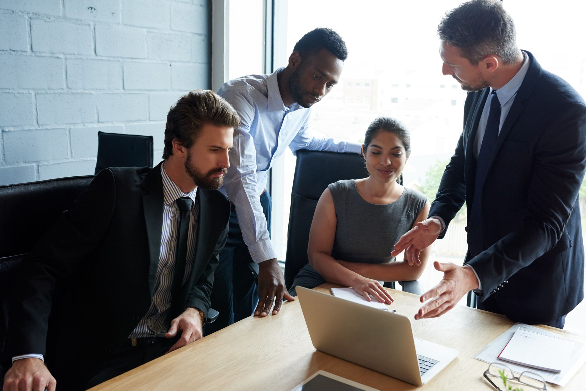 Group of business professionals gathered around a laptop, discussing a project.