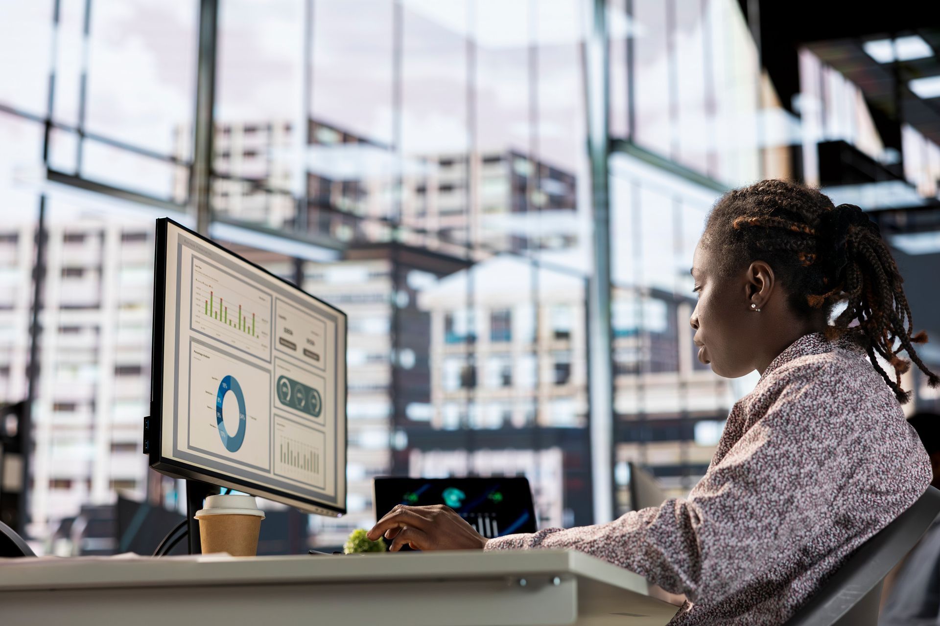 Person working at a computer, analyzing data with city background.
