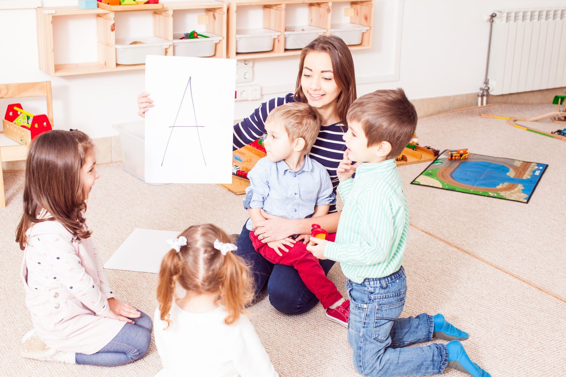 Teacher showing letter "A" to children in a classroom.
