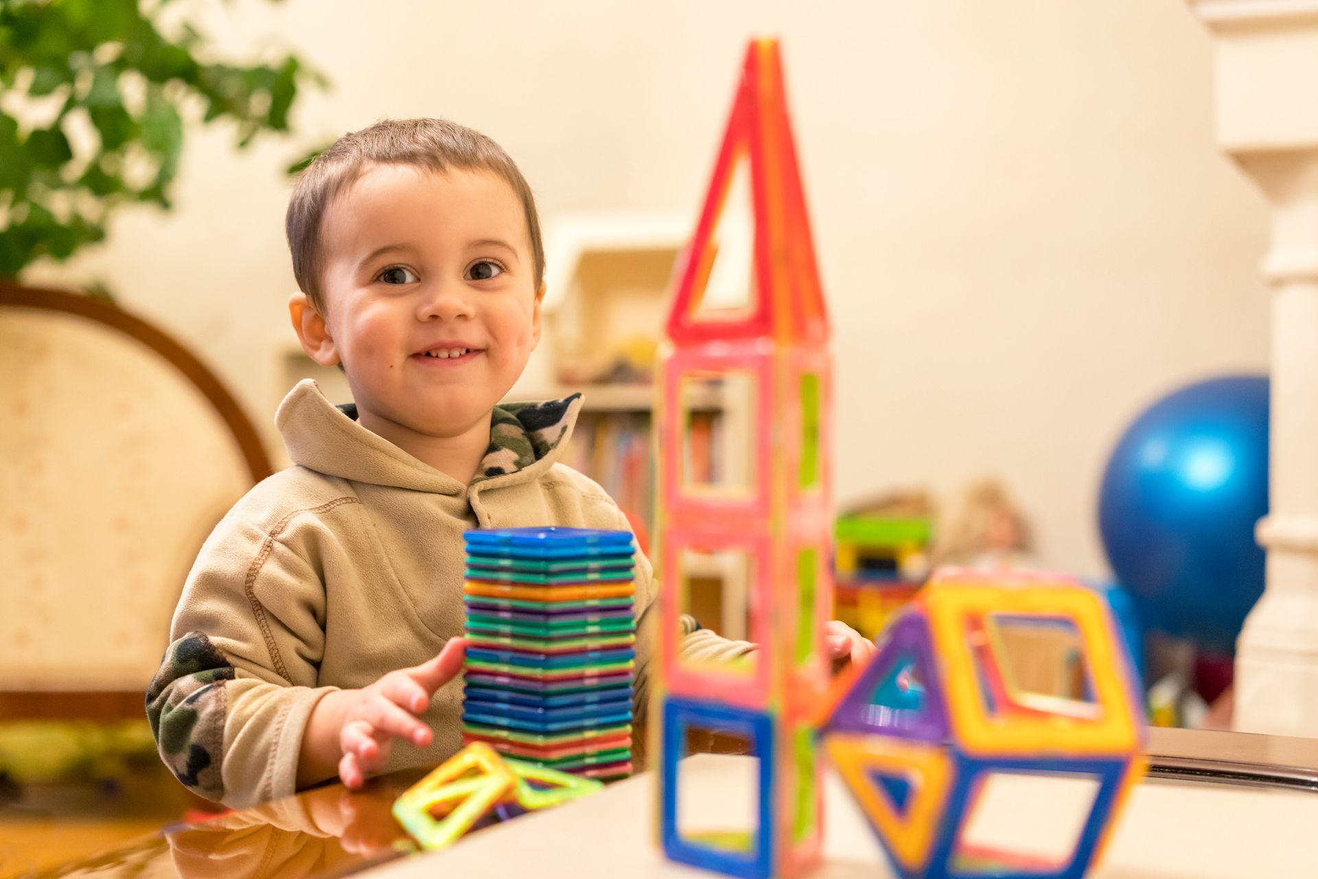 Smiling child building with magnetic blocks at a table.
