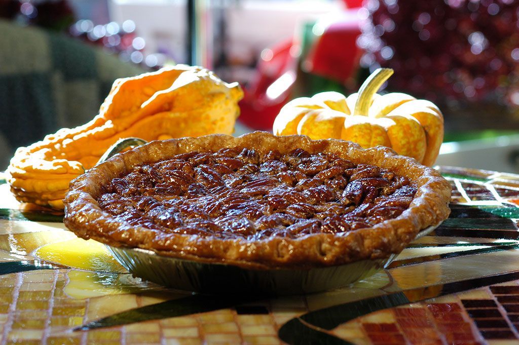 A pecan pie sits on a table next to pumpkins