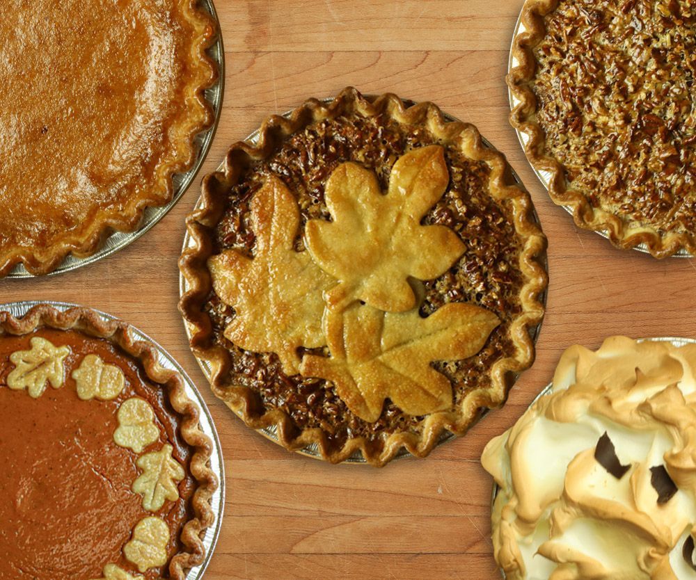 A variety of pies are sitting on a wooden table