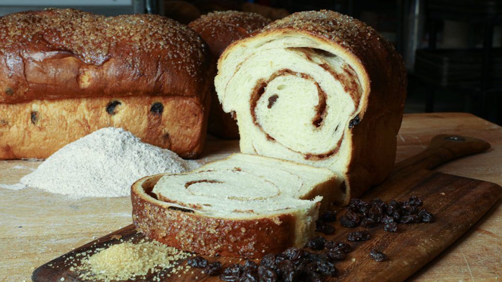A loaf of bread is sitting on a wooden cutting board.