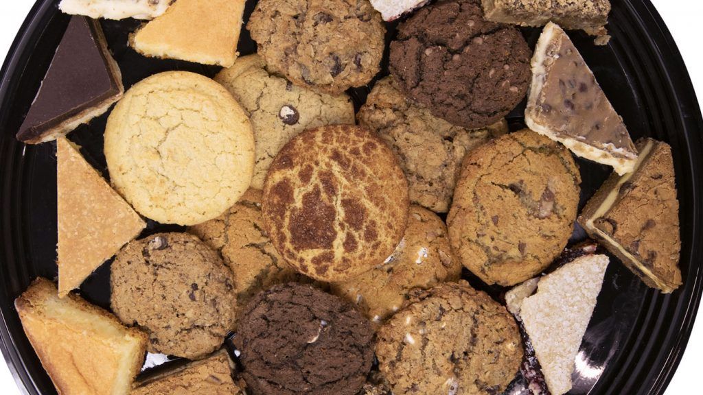 A black tray filled with a variety of cookies and desserts.