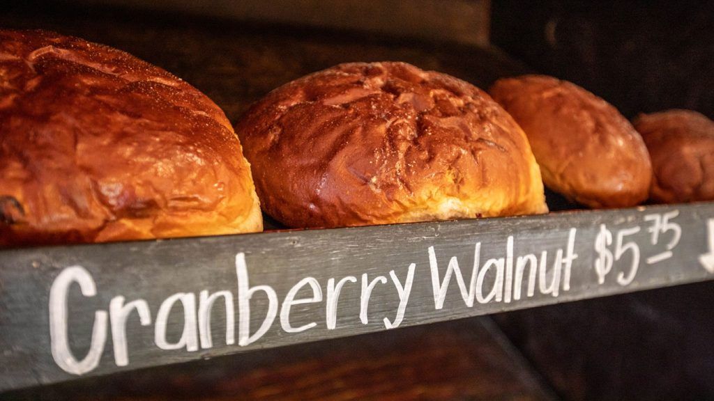 A row of cranberry walnut bread sitting on top of a wooden shelf.