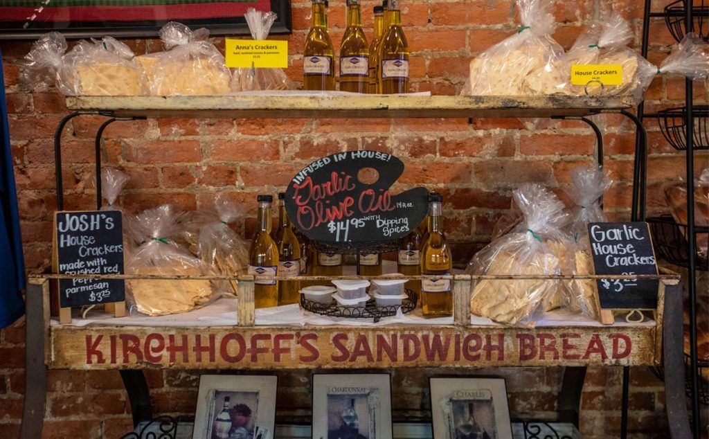 A shelf filled with sandwich bread and bottles of oil.