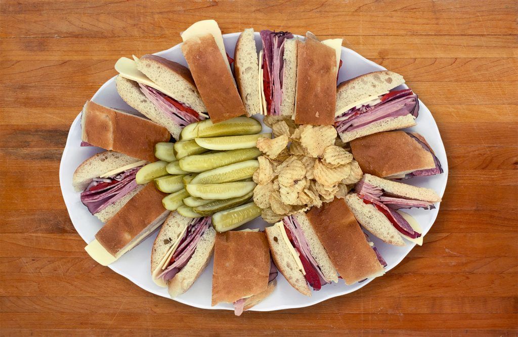 A white plate topped with sandwiches and pickles on a wooden table.