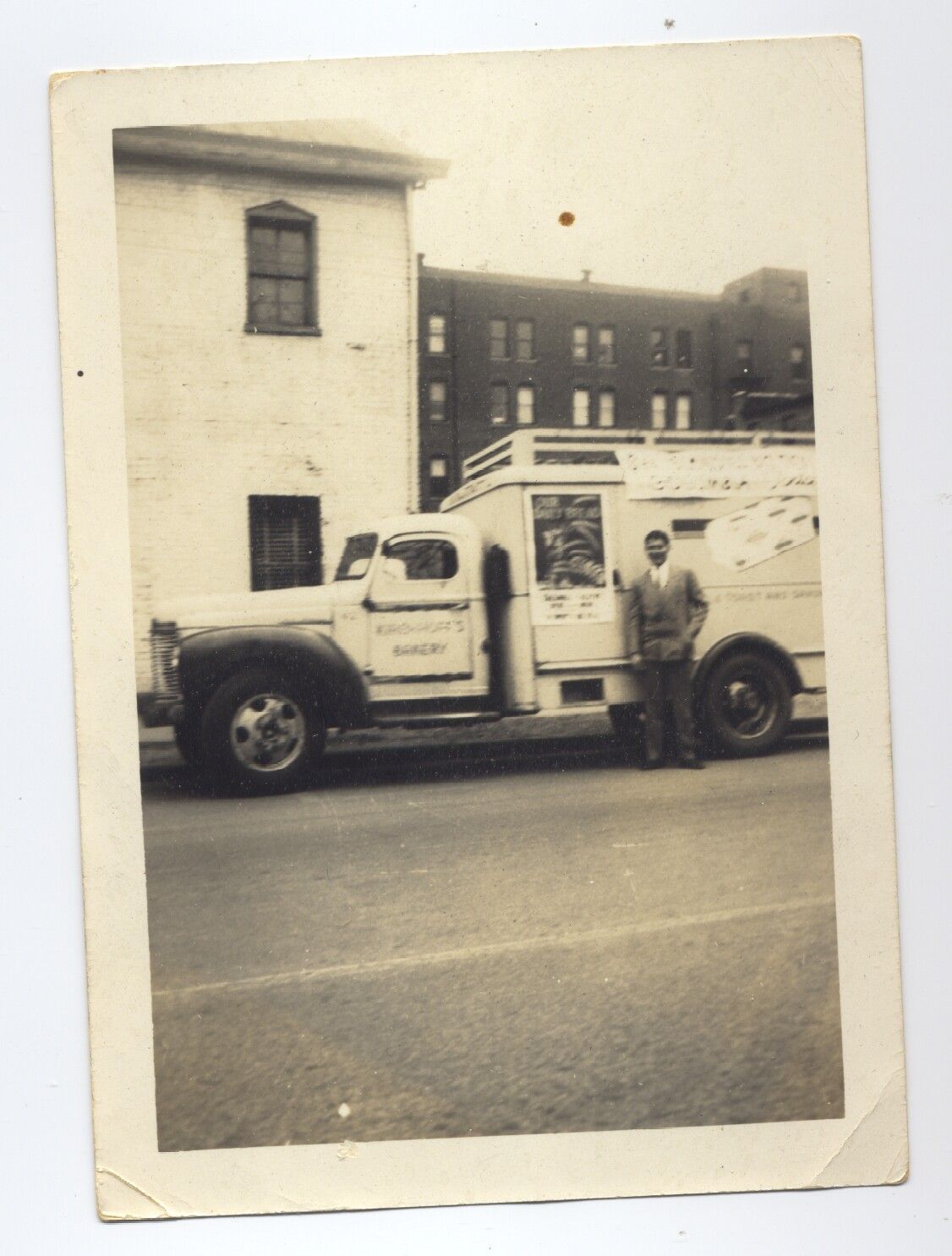 A black and white photo of a man standing next to a white truck