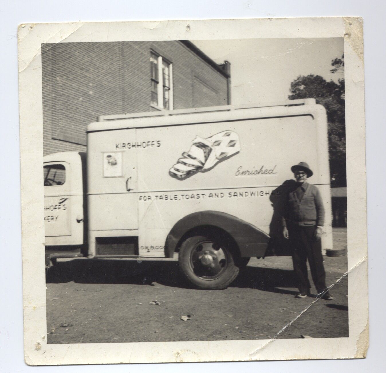 A black and white photo of a man standing in front of a sandwich truck
