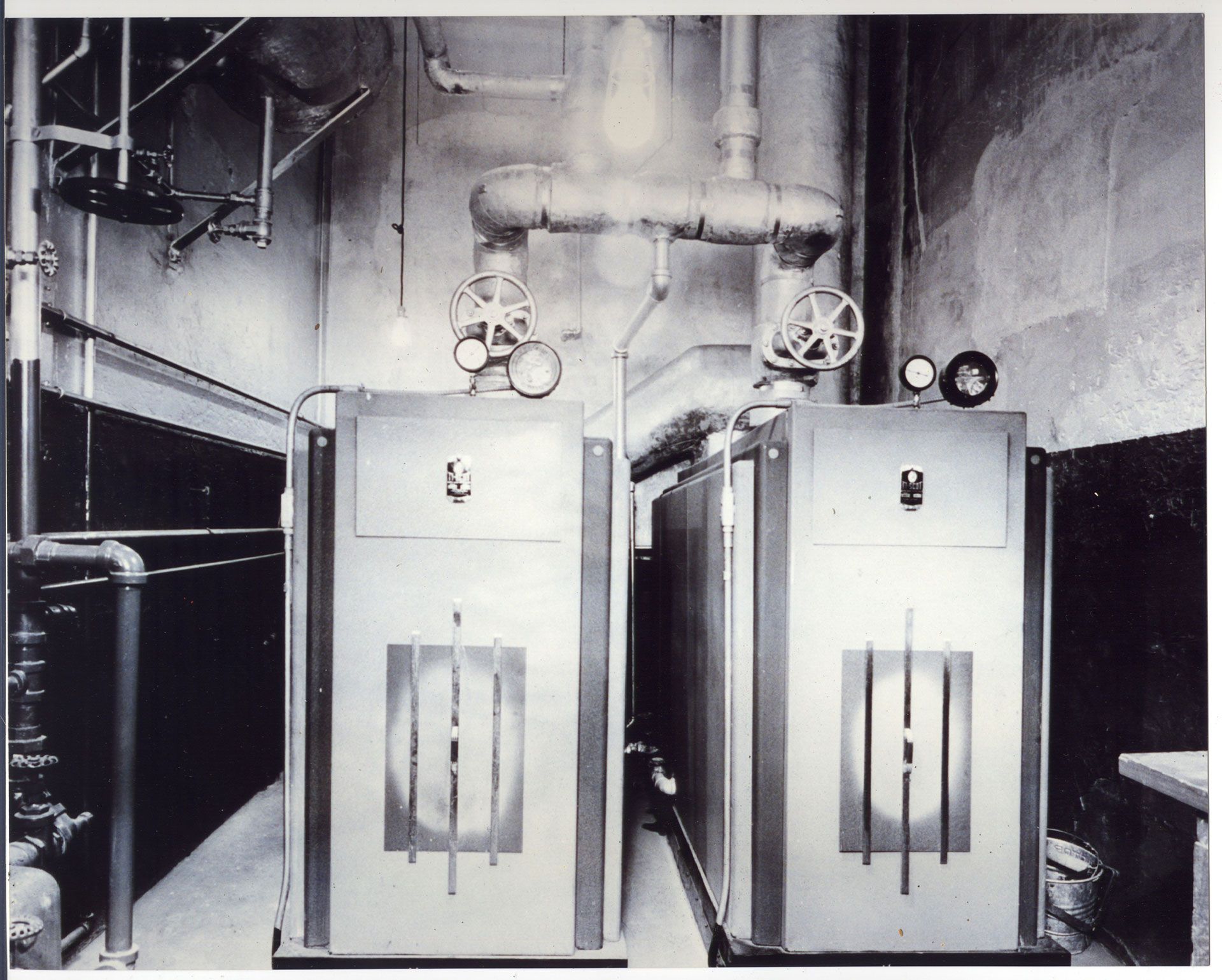 A black and white photo of two boilers in a room