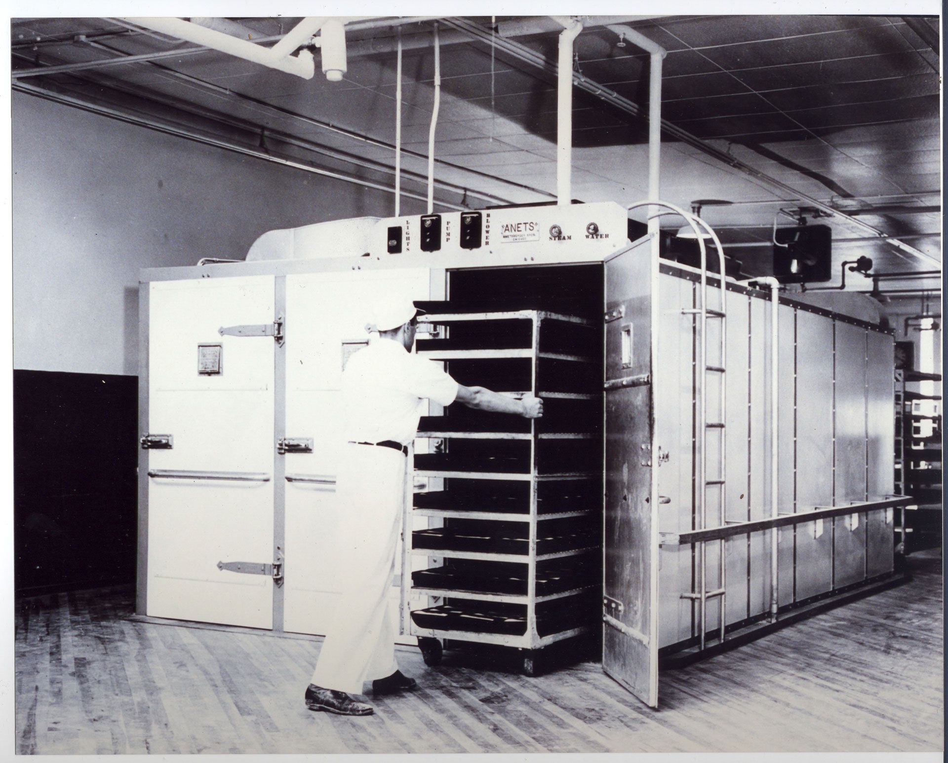 A black and white photo of a man standing in front of a refrigerator