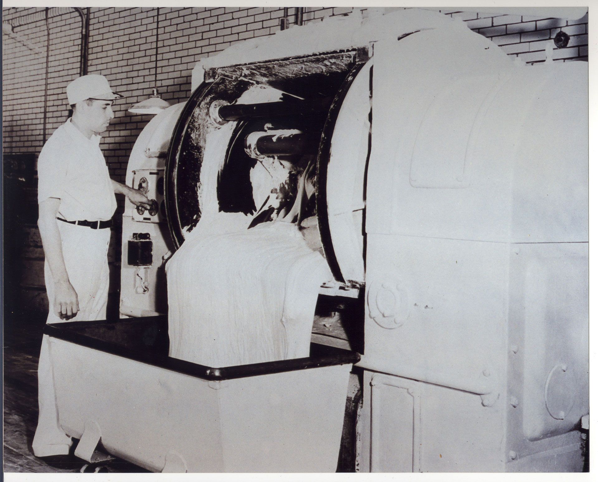 A black and white photo of a man working on a machine