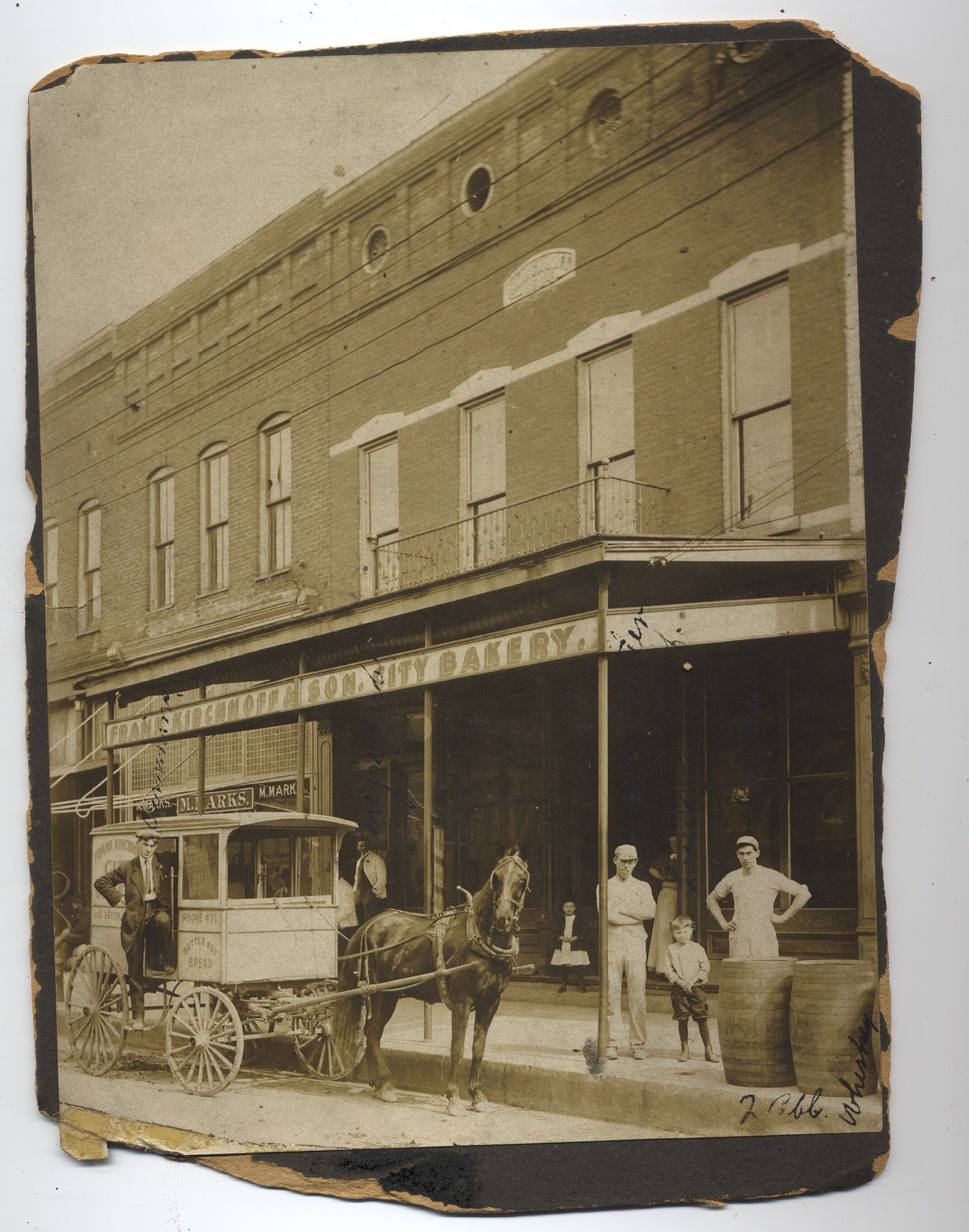 A black and white photo of a horse drawn carriage in front of a building