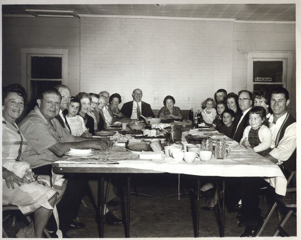A black and white photo of a group of people sitting around a table