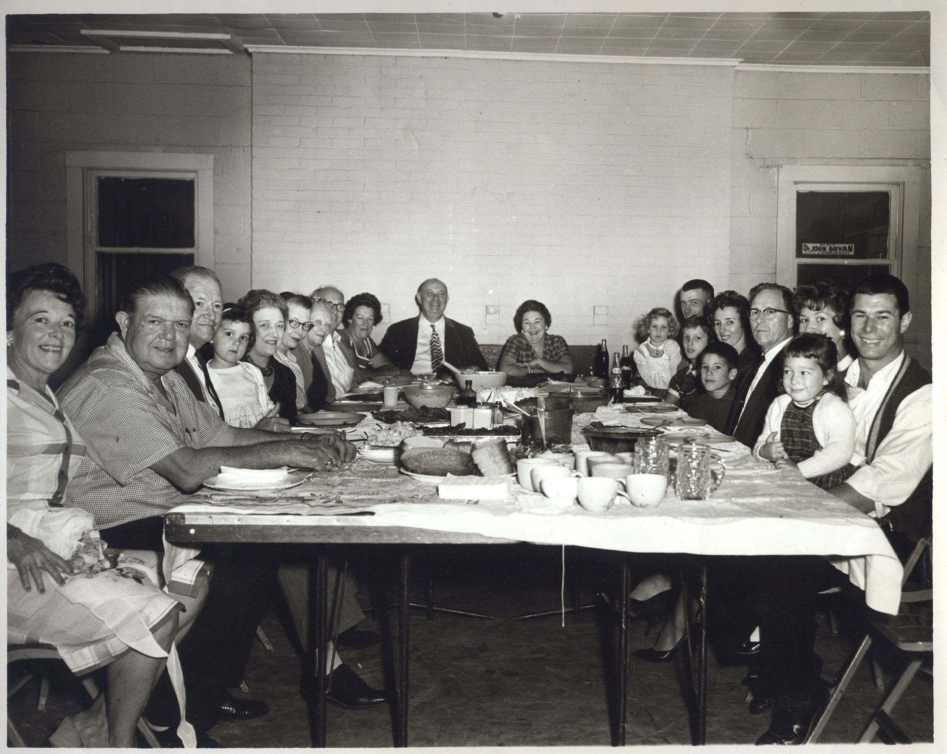 A black and white photo of a group of people sitting around a table