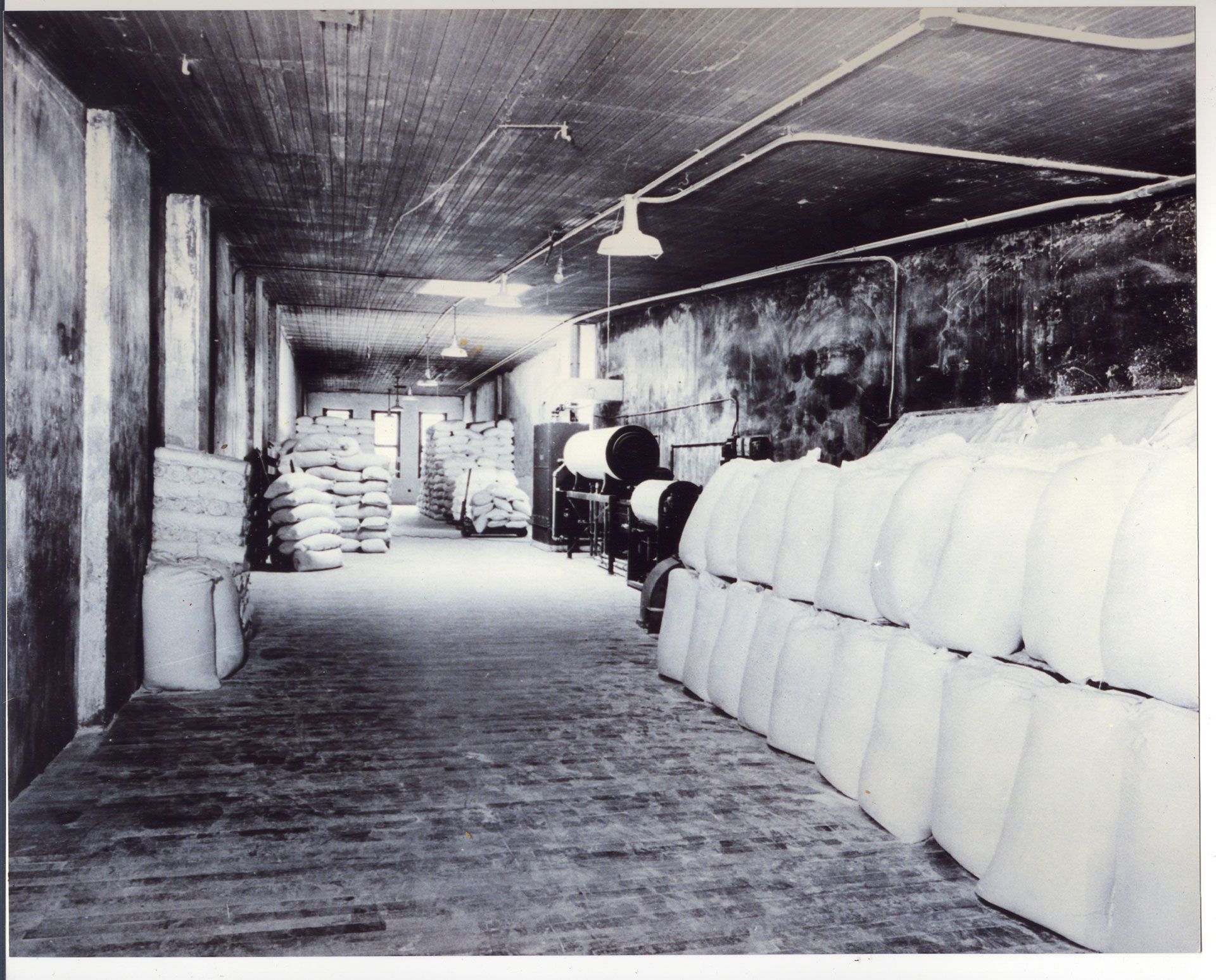 A black and white photo of a warehouse filled with bags
