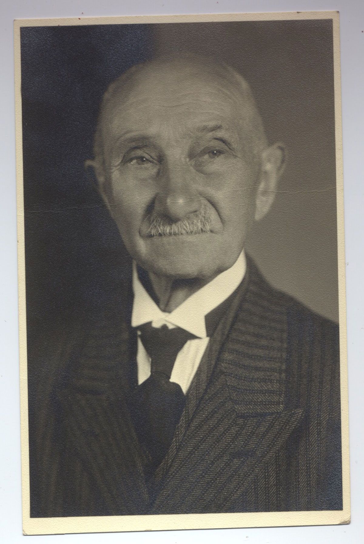 A black and white photo of an older man in a suit and tie