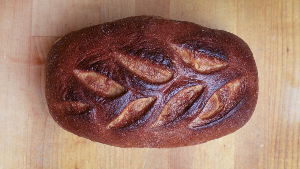 A loaf of bread is sitting on a wooden table.