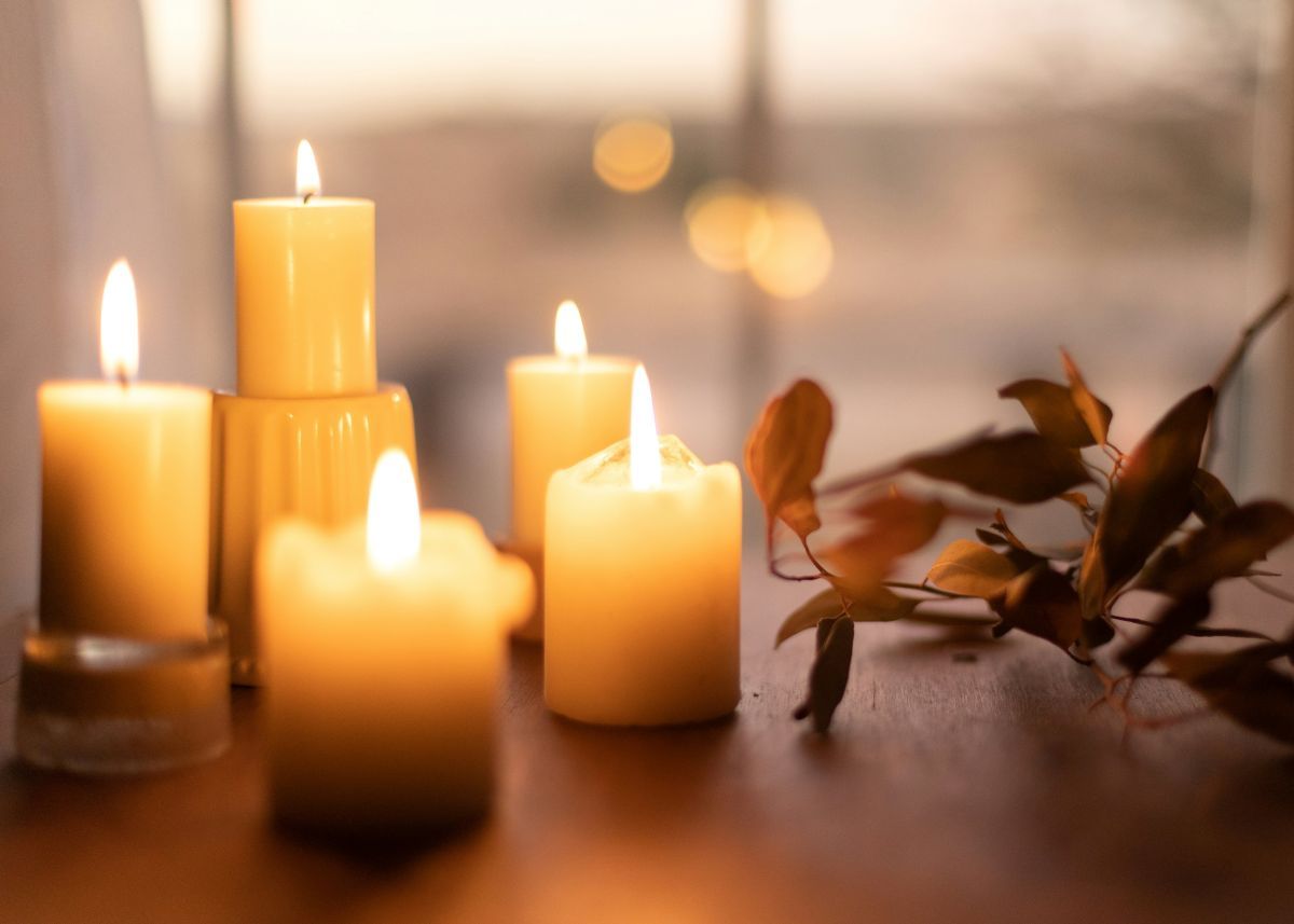 A group of lit candles sitting on top of a wooden table.