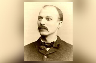 A black and white photo of a man with a mustache and bow tie.