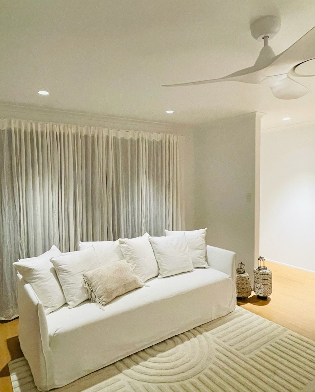 White Living Room With Couch, Curtains, and Ceiling Fan — Grant Murphy Electrical in Kingscliff, NSW