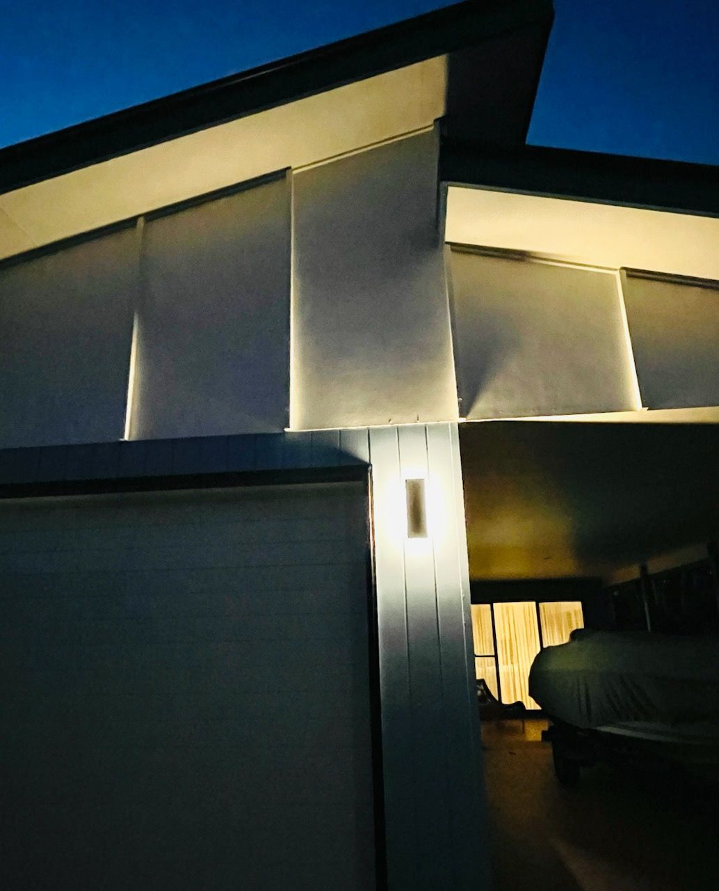 Exterior of a building lit at dusk, featuring a white facade and a glowing rectangular wall light — Grant Murphy Electrical in Kingscliff, NSW