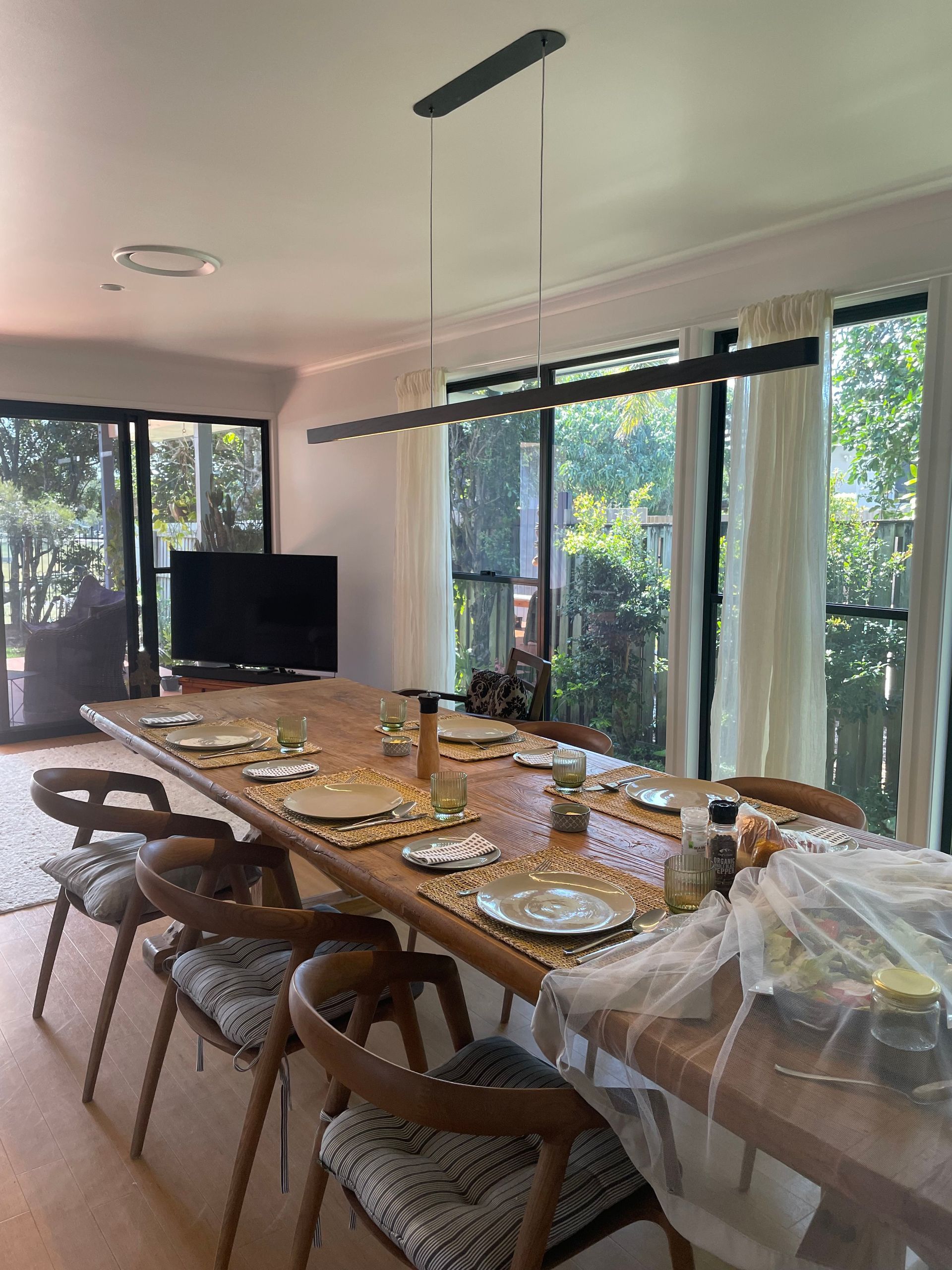 Long Wooden Dining Table Set for a Meal, With Chairs, a Long Light Fixture — Grant Murphy Electrical in Kingscliff, NSW
