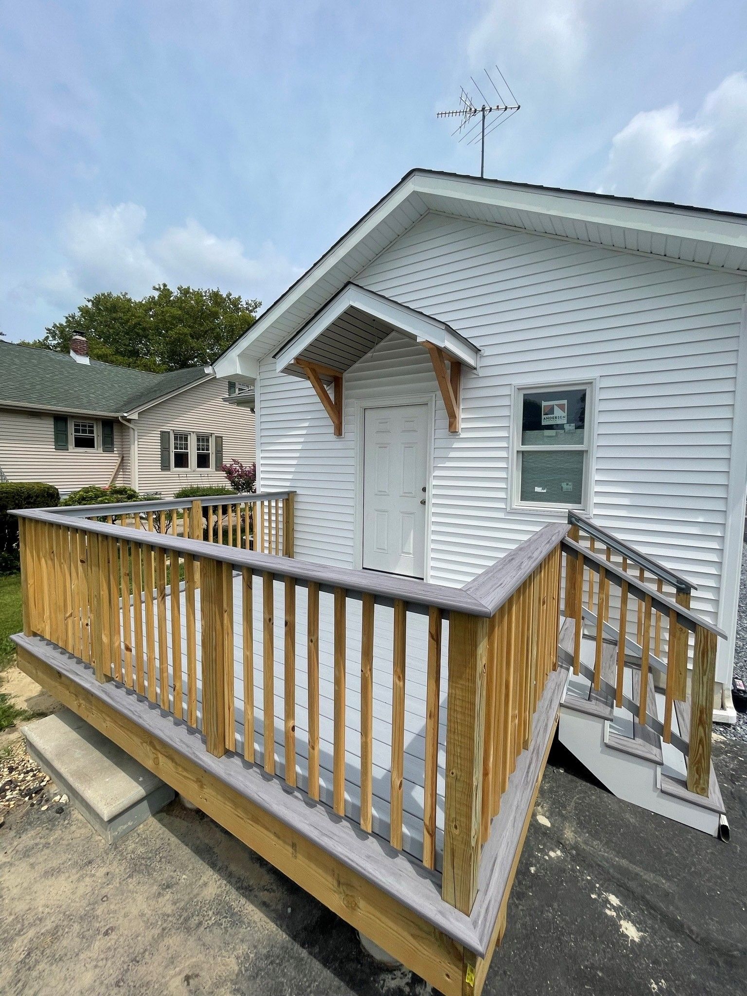 a white house with a wooden deck and stairs