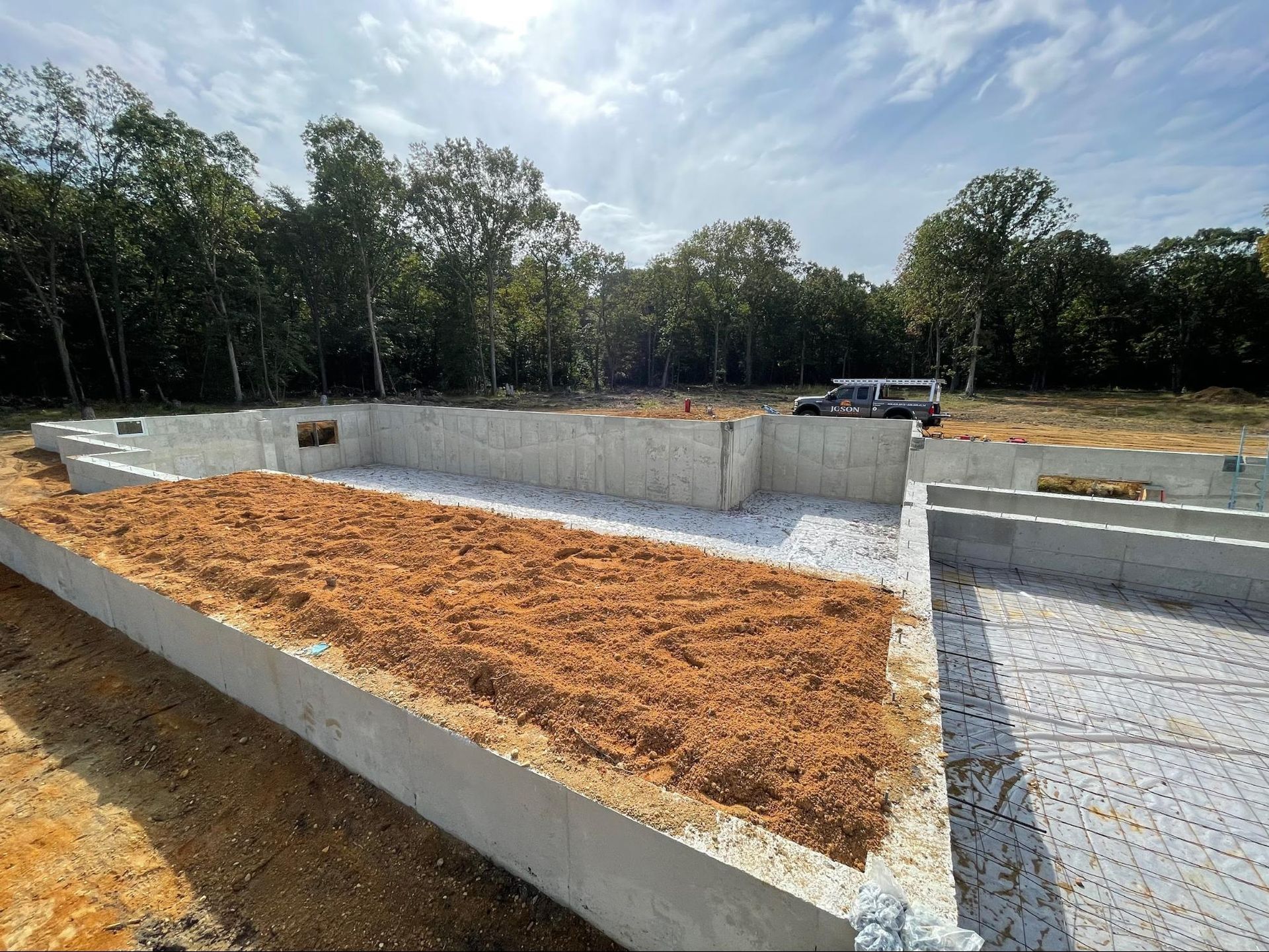 a construction site with a lot of dirt and trees in the background