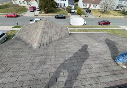 man taking picture of new roof with neighborhood in the background