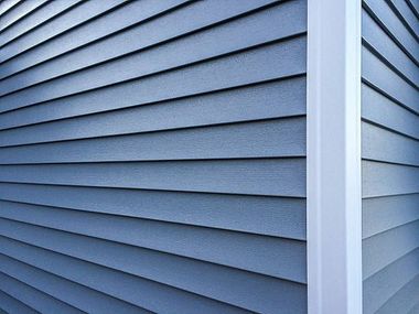 a close up of a blue siding on a house with a white trim