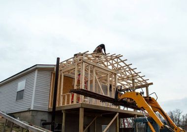 a man is working on the roof of a house with an addition being built 