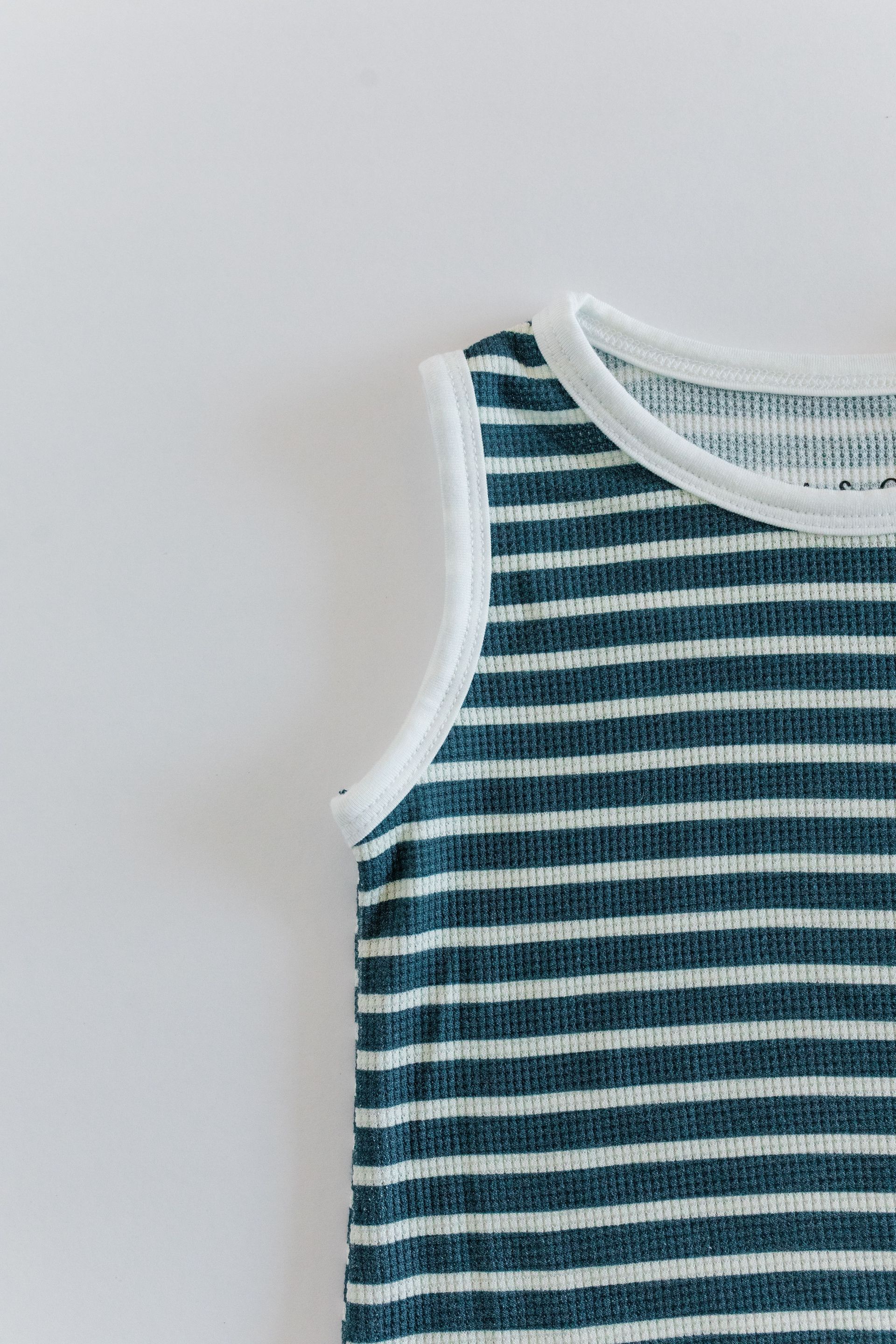 Close-up of a blue and white striped tank top, edged in white, against a white background.