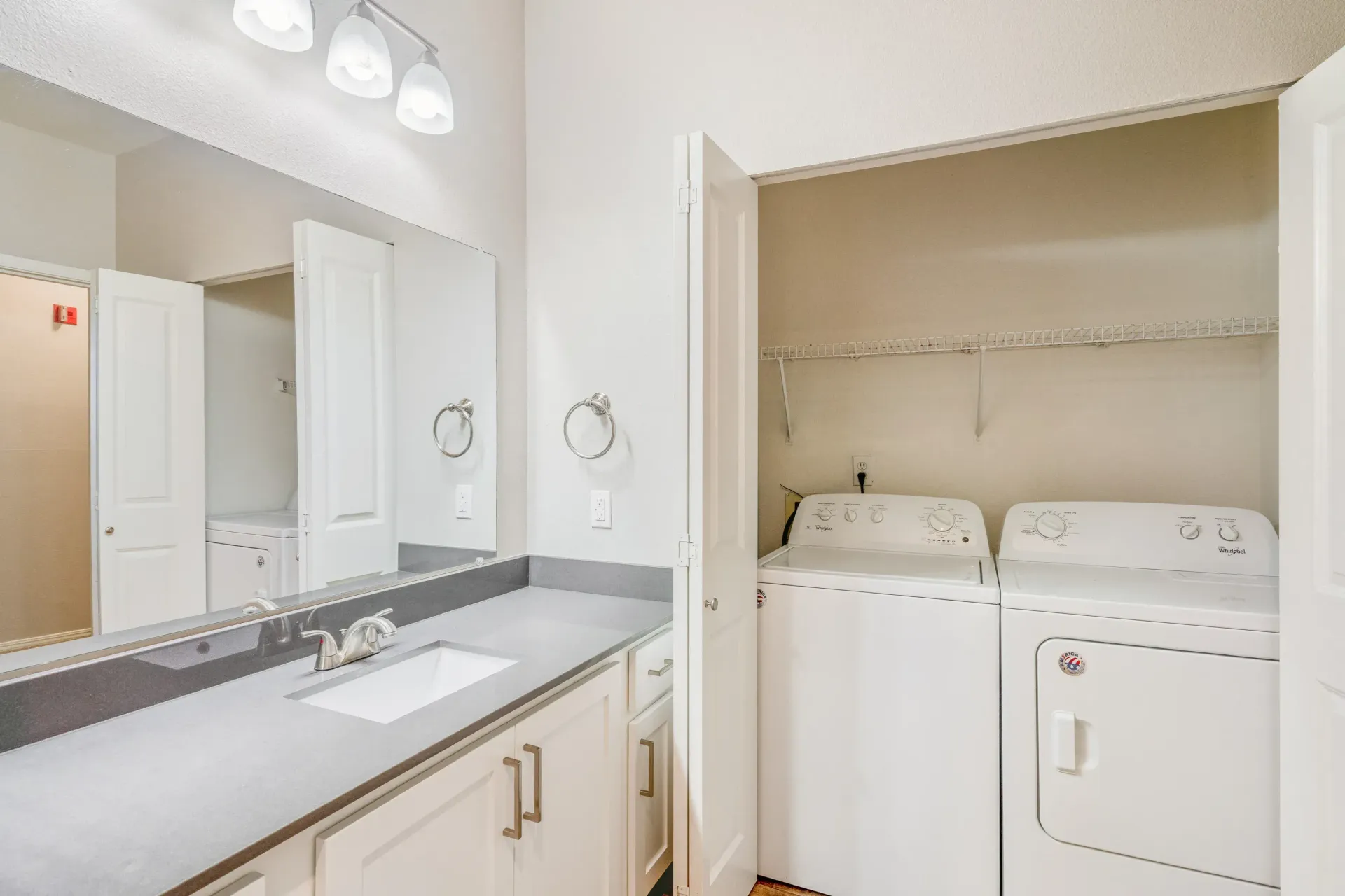 Bathroom vanity with sink and a laundry closet housing a washer and dryer.