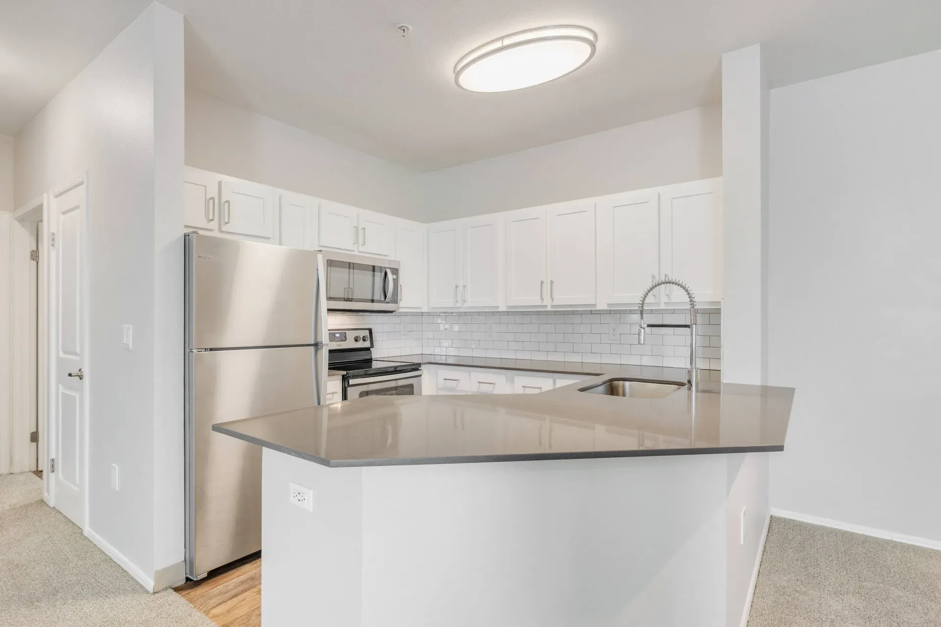 Bright modern kitchen with white cabinets, stainless steel appliances, and a large island.