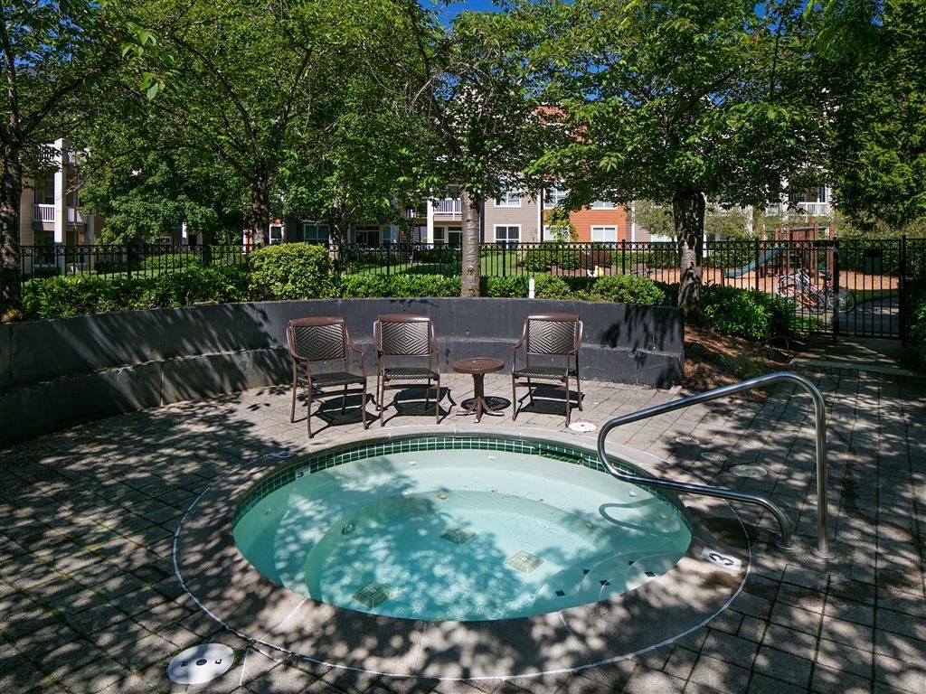 Circular outdoor pool with four metal chairs and a small table in a shaded courtyard.