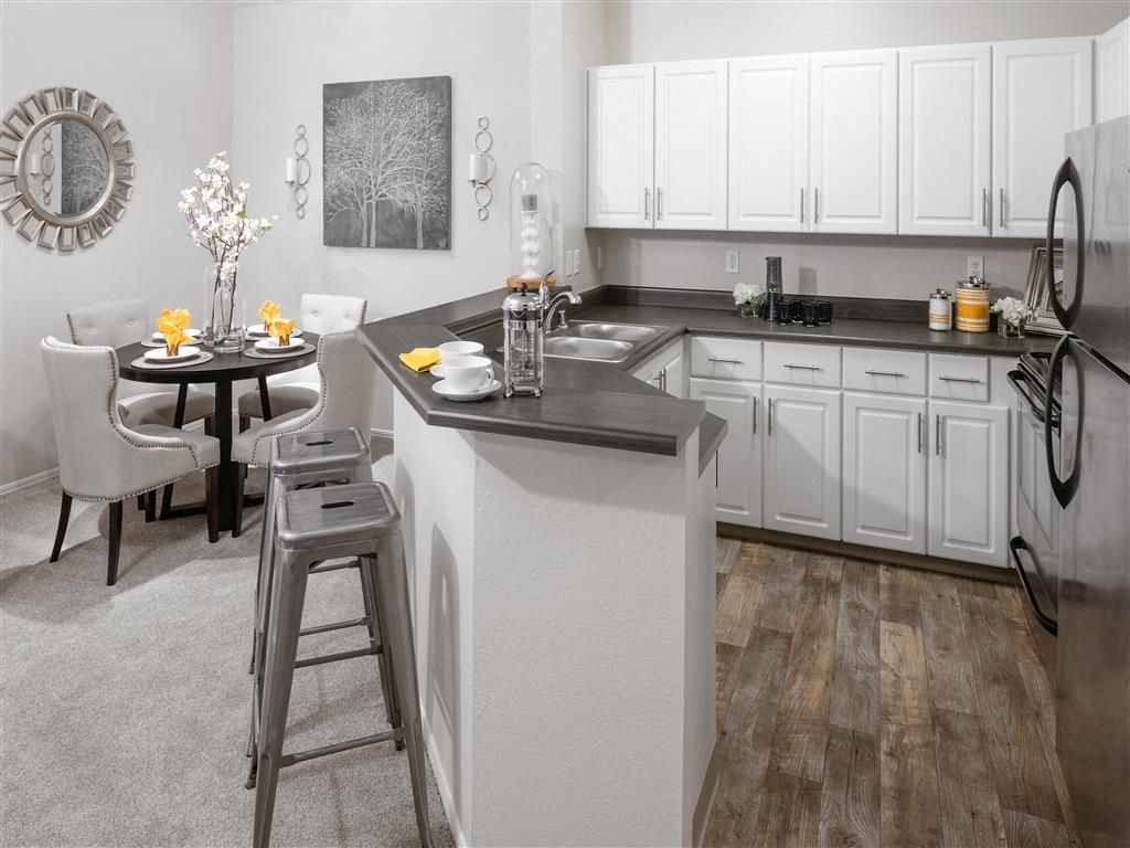Modern white kitchen with gray countertops, an island breakfast bar, and a round dining table.
