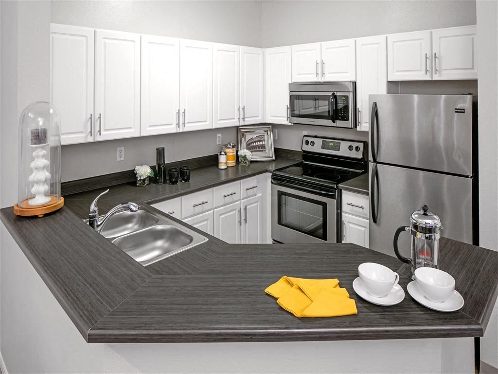 U-shaped kitchen with white cabinets, stainless steel appliances, and a dark wraparound counter.