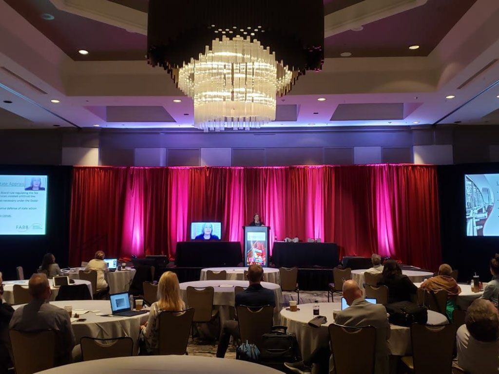 A large room filled with people sitting at tables with laptops.