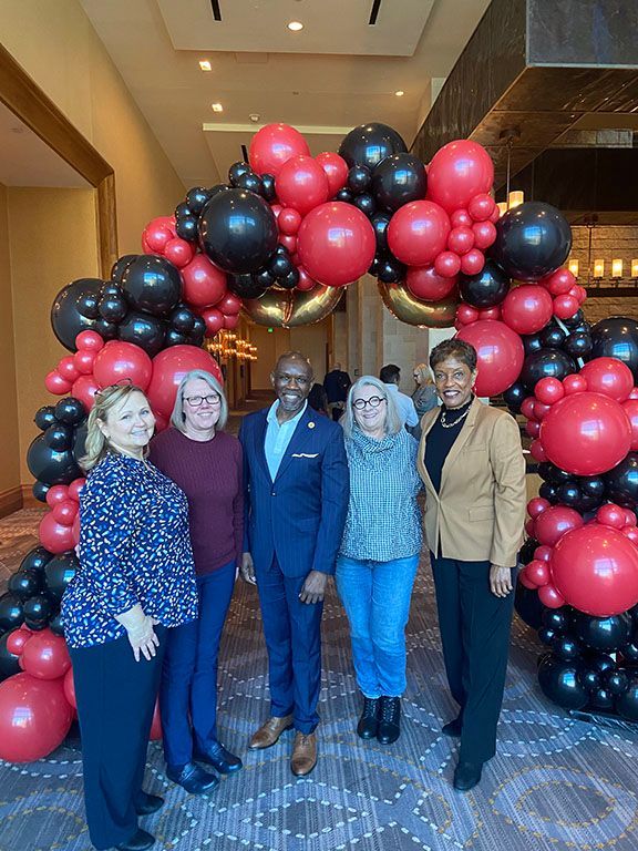 A group of people standing in front of a balloon arch.