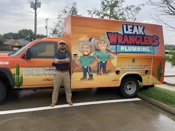 A man is standing in front of a leak wranglers plumbing truck