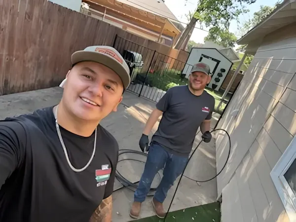 Two men are standing next to each other in front of a house