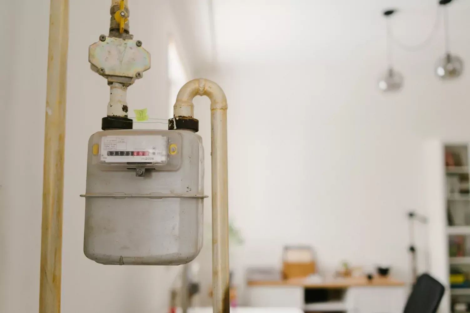 A gas meter is hanging from a pipe in a living room.