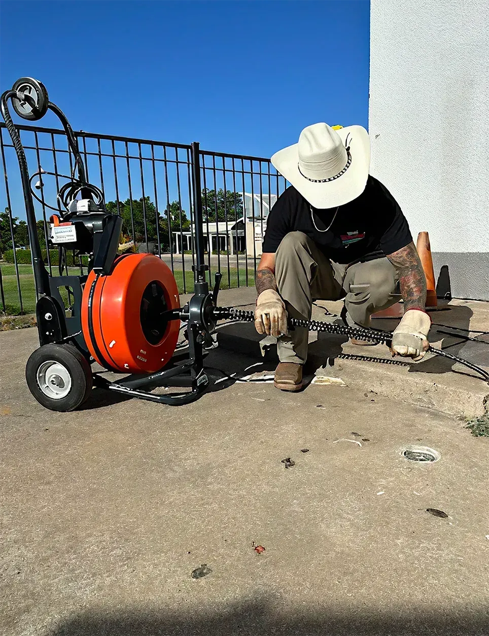 A man in a cowboy hat is kneeling down next to a machine.