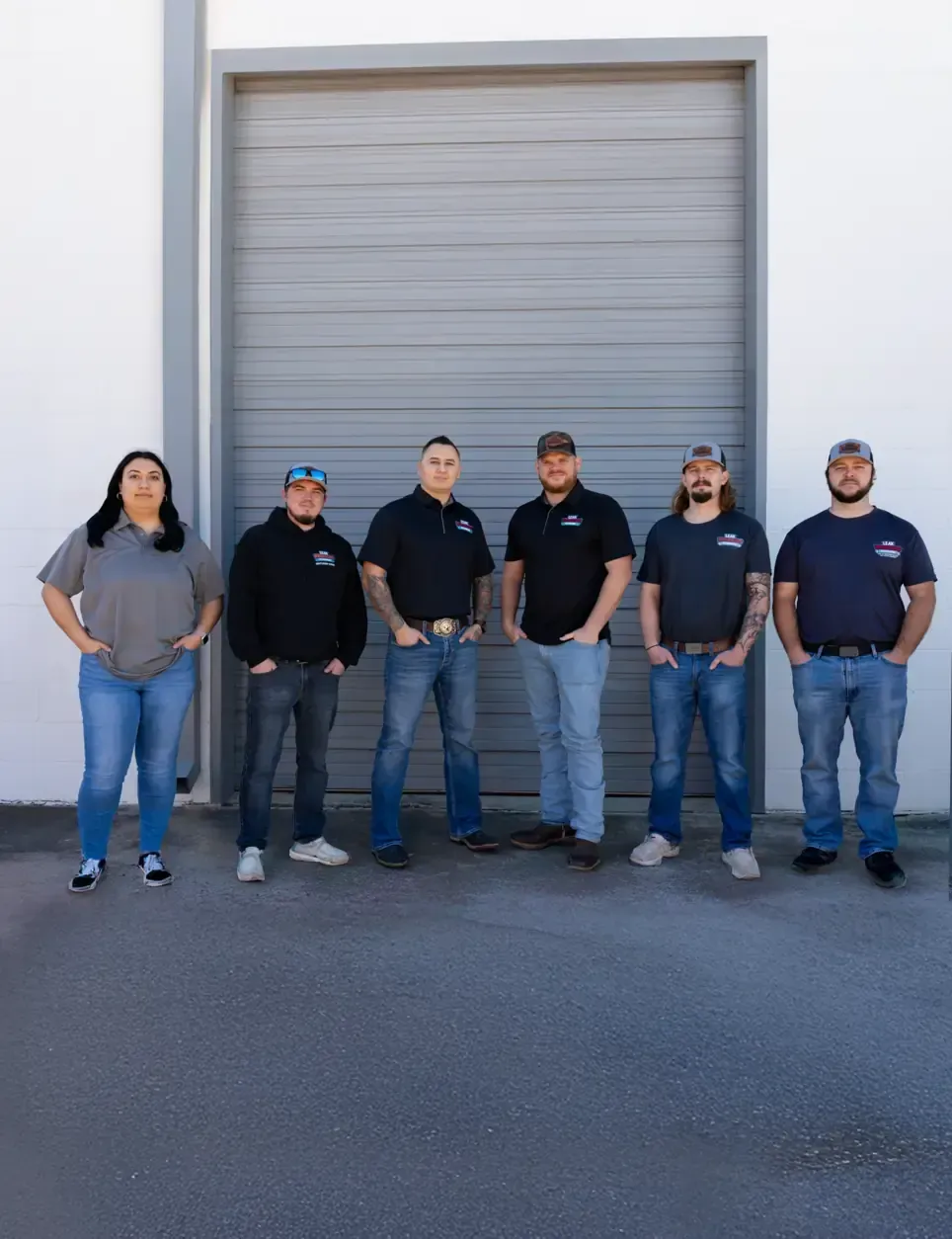 A group of people standing in front of a garage door.