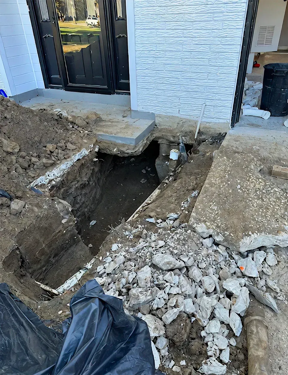 A person is digging a hole in the ground in front of a house.
