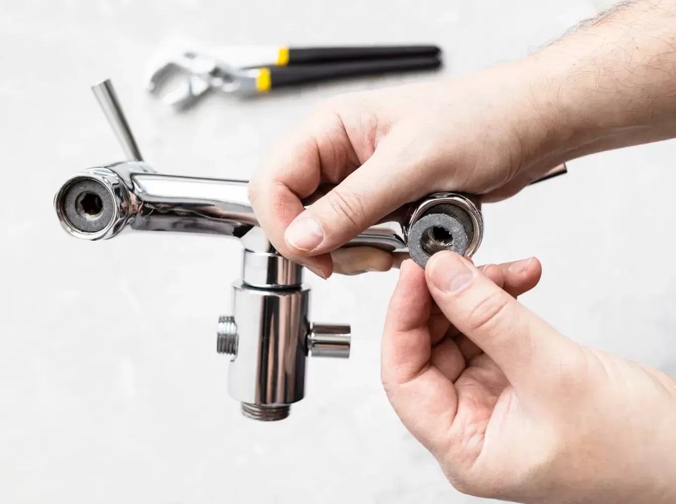 A person is fixing a faucet with a wrench.